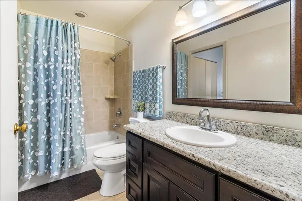 a bathroom with a granite countertop sink toilet a mirror a vanity and shower