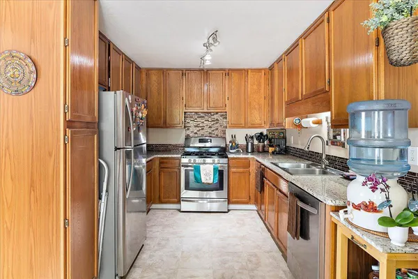 a kitchen with stainless steel appliances granite countertop a refrigerator a stove and a sink with dishwasher
