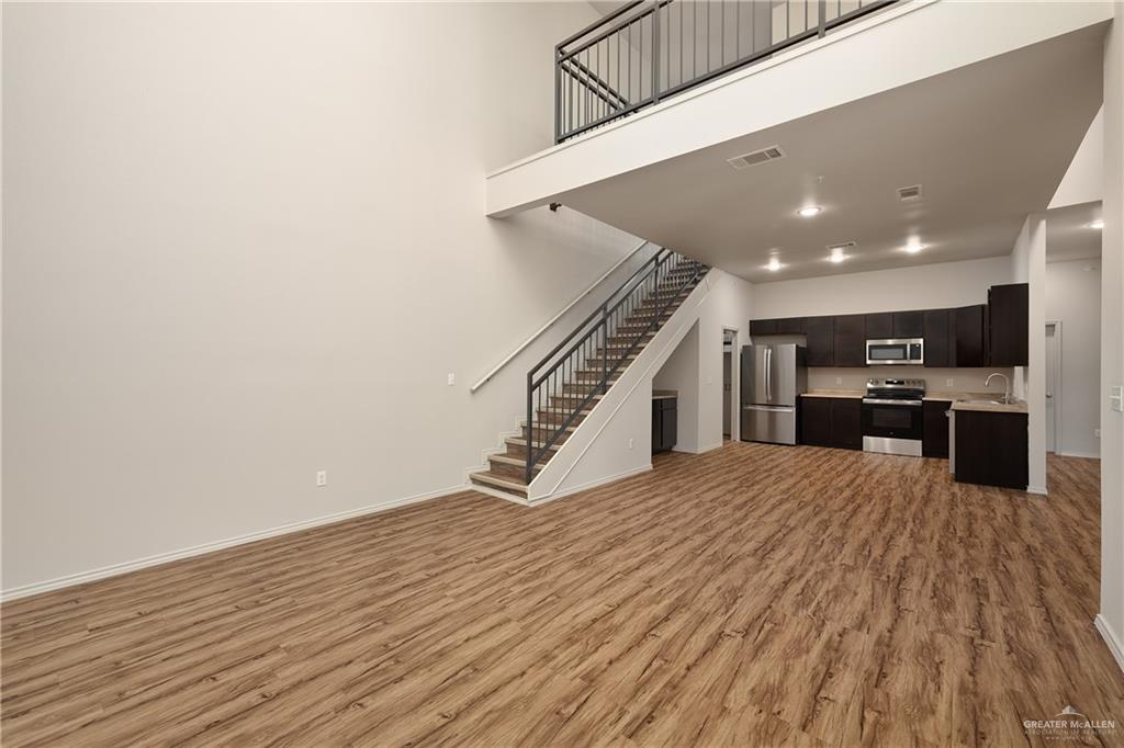 810 South Taylor Road Mission, TX 78572 - Photo 9 of 17 Unfurnished living room with a high ceiling, light wood finished floors, and stairs
