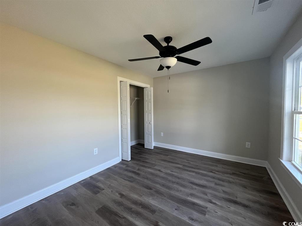 123 Alford Drive Loris, SC 29569 - Photo 11 of 13 Unfurnished bedroom with dark wood finished floors, a closet, and a ceiling fan