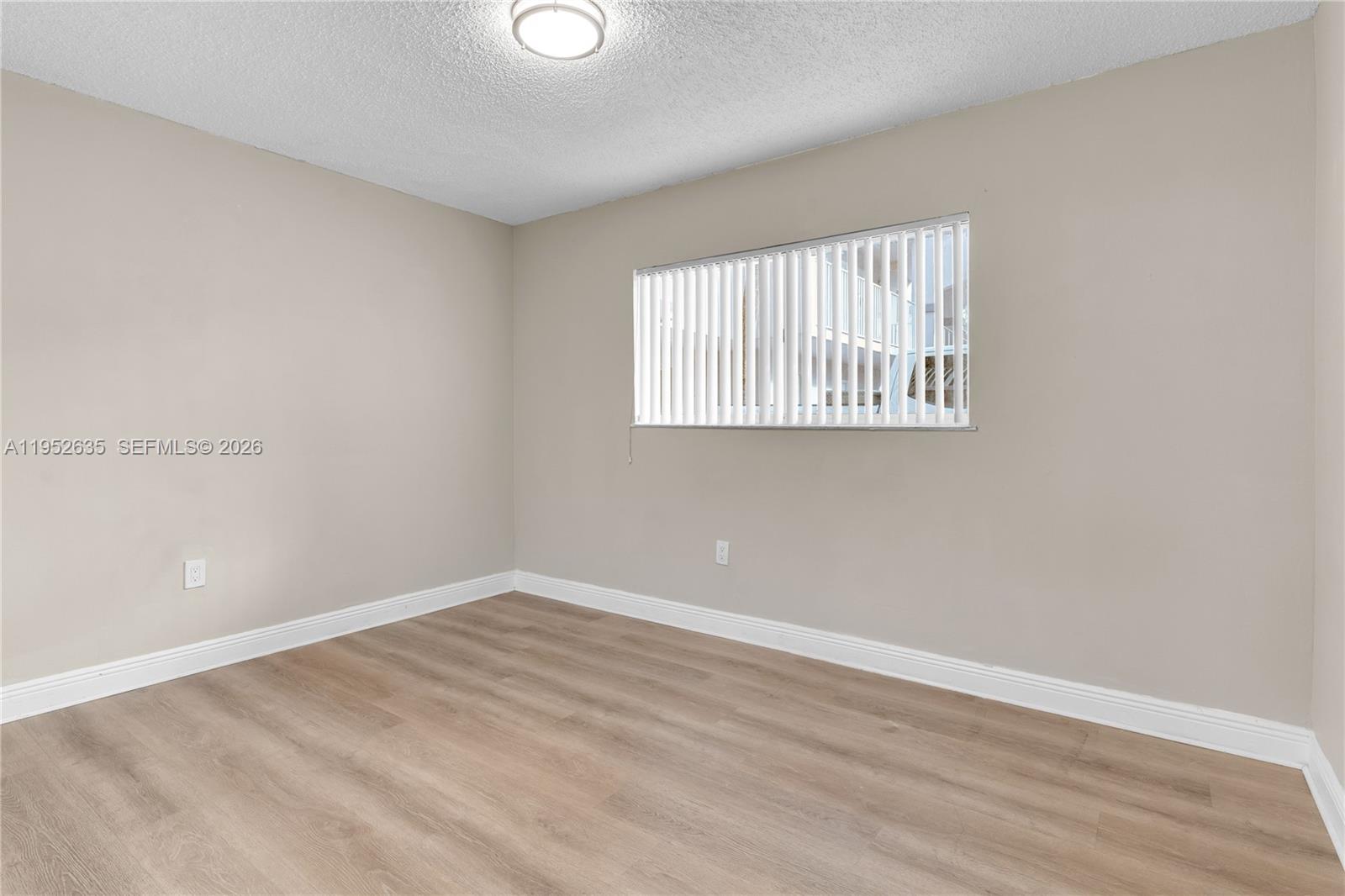 2690 West 76th Street, Unit 104 Hialeah, FL 33016 - Photo 12 of 25 a view of an empty room with wooden floor and a window