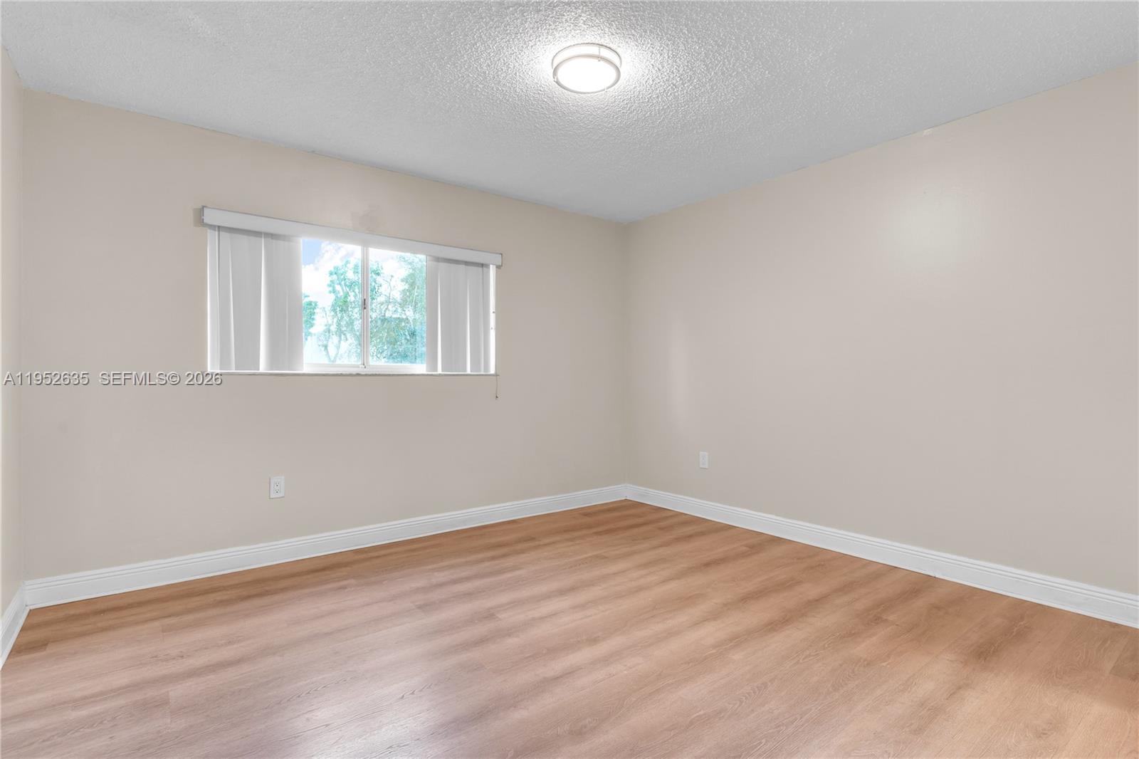 2690 West 76th Street, Unit 104 Hialeah, FL 33016 - Photo 17 of 25 an empty room with wooden floor and windows