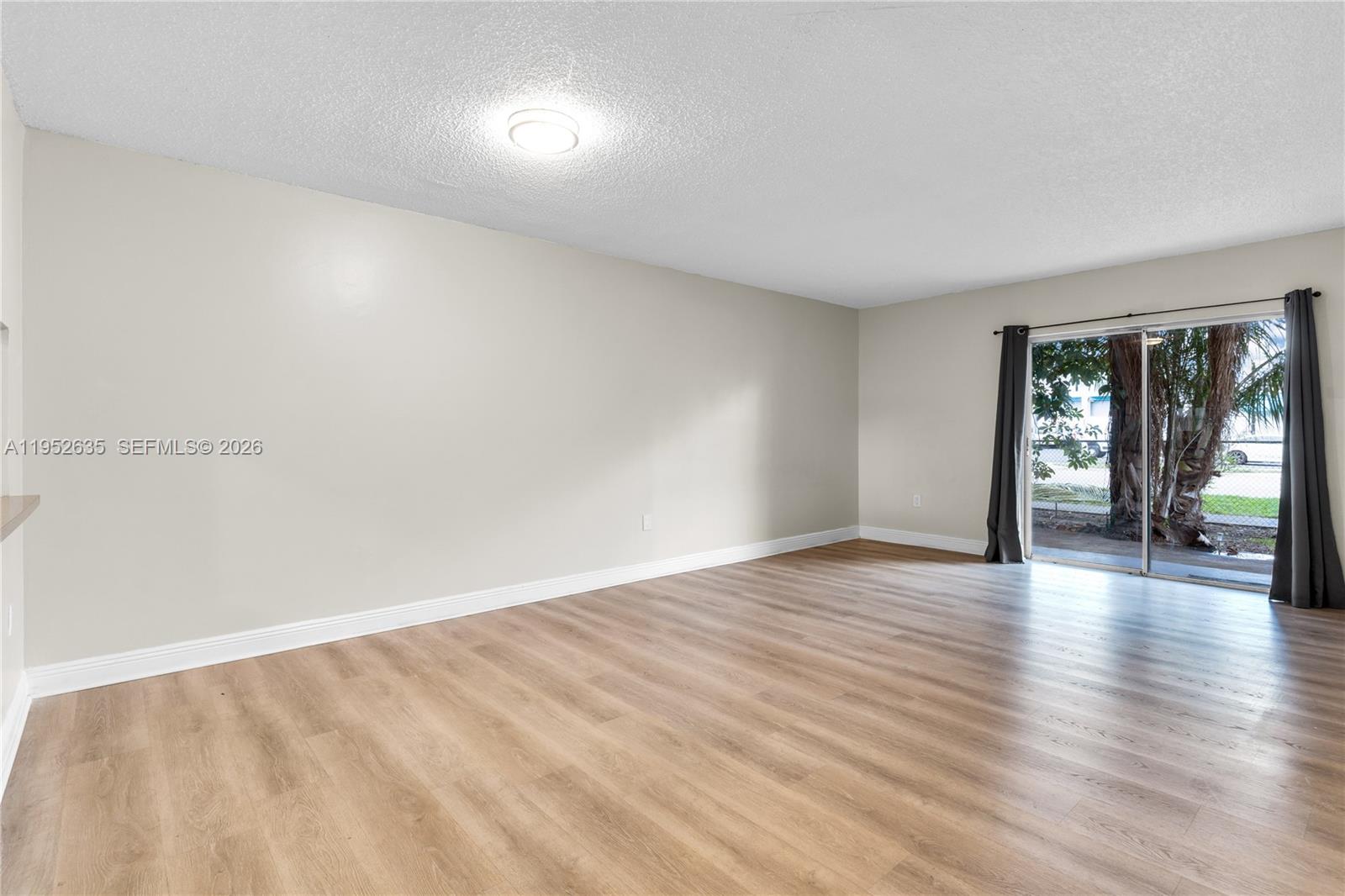 2690 West 76th Street, Unit 104 Hialeah, FL 33016 - Photo 5 of 25 a view of an empty room with wooden floor and a window