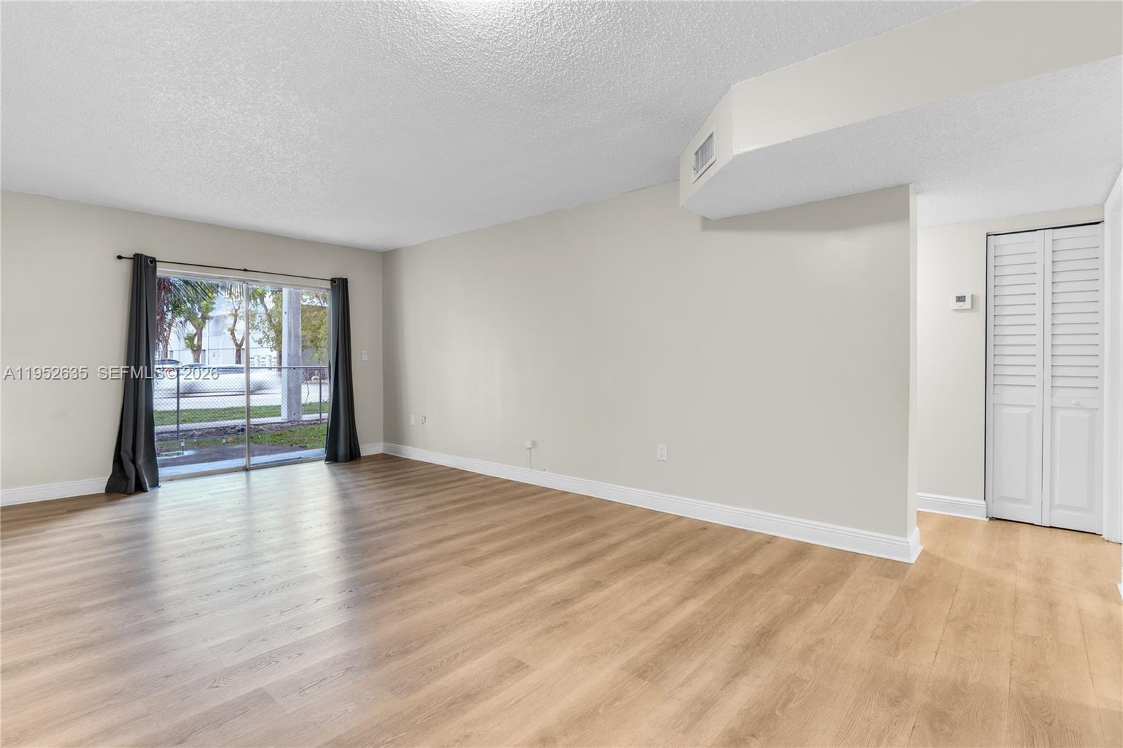 2690 West 76th Street, Unit 104 Hialeah, FL 33016 - Photo 6 of 25 a view of an empty room with wooden floor and a window