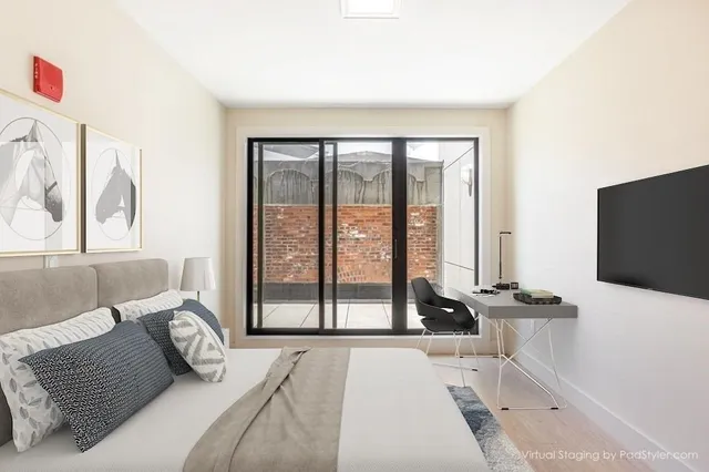 a bedroom with a bed and a flat tv screen next to a large window