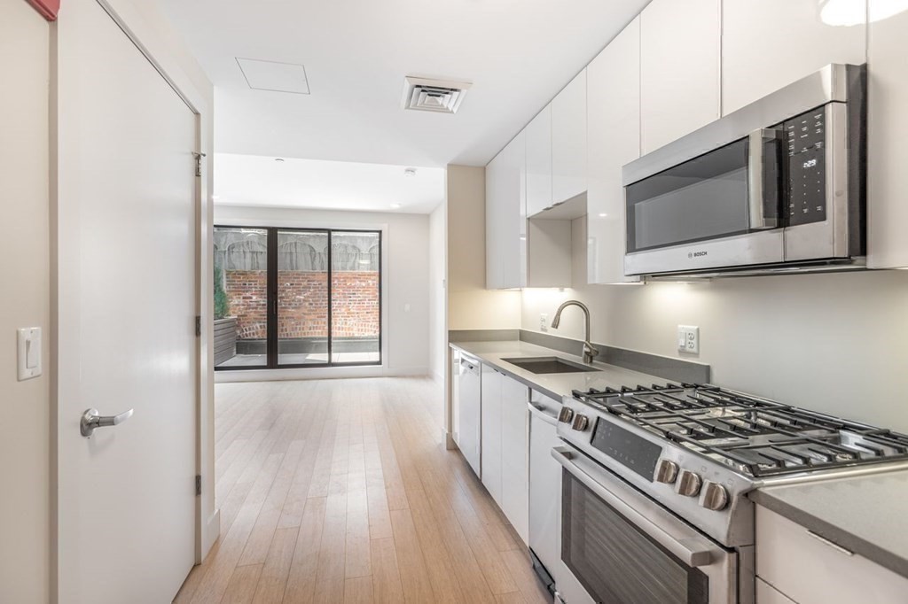 121 Portland Street, Unit 7O8 Boston, MA 02114 - Photo 26 of 40 a kitchen with stainless steel appliances granite countertop a stove and a microwave