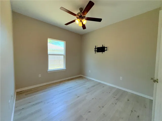 an empty room with windows and fan