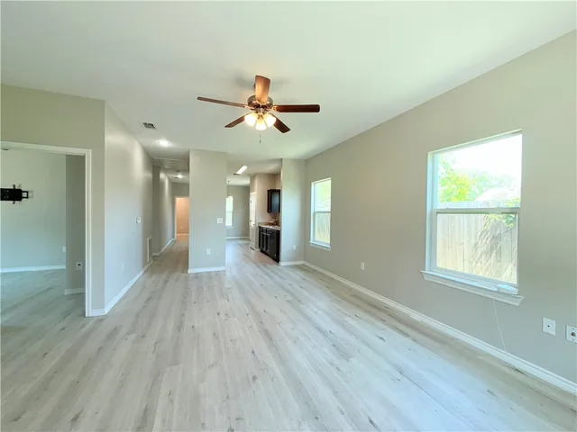 a view of a big room with wooden floor and windows