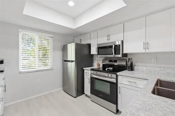 a kitchen with cabinets stainless steel appliances and wooden floor