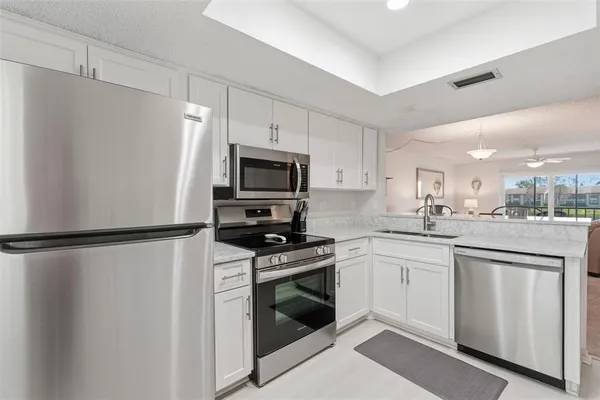 a kitchen with white cabinets and refrigerator