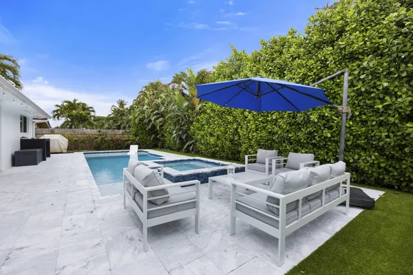 a view of a patio with chairs and a table under an umbrella