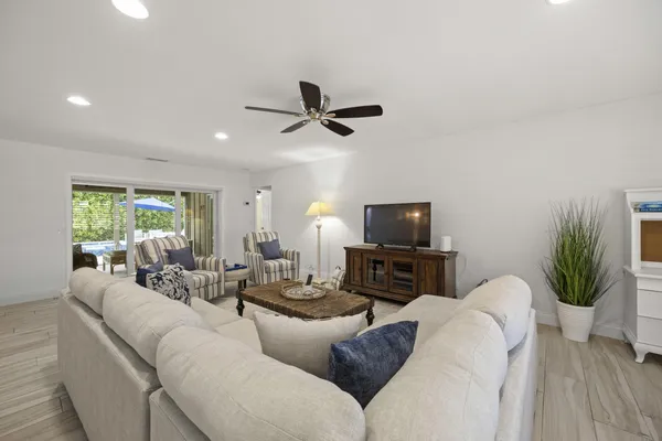 a living room with furniture a ceiling fan and a flat screen tv