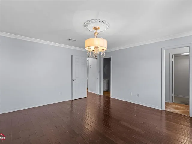 an empty room with wooden floor chandelier and glass door