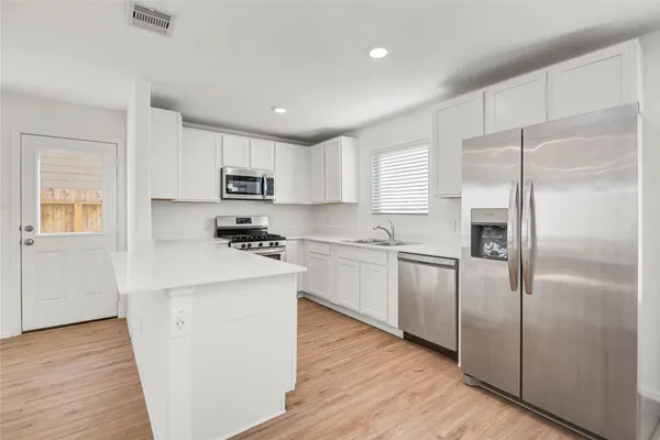 a kitchen with a refrigerator a stove top oven and wooden floor
