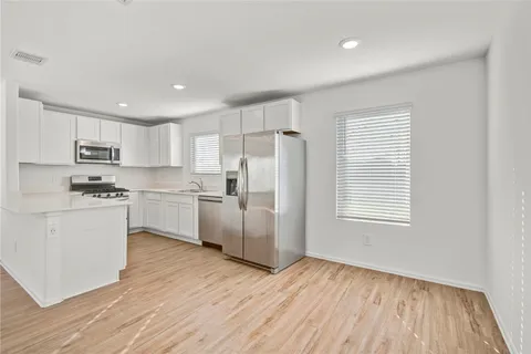 a kitchen with white cabinets and wooden floor