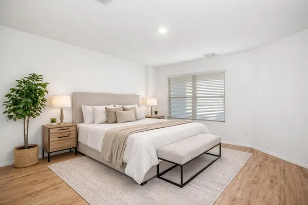 a bedroom with a large bed and a potted plant