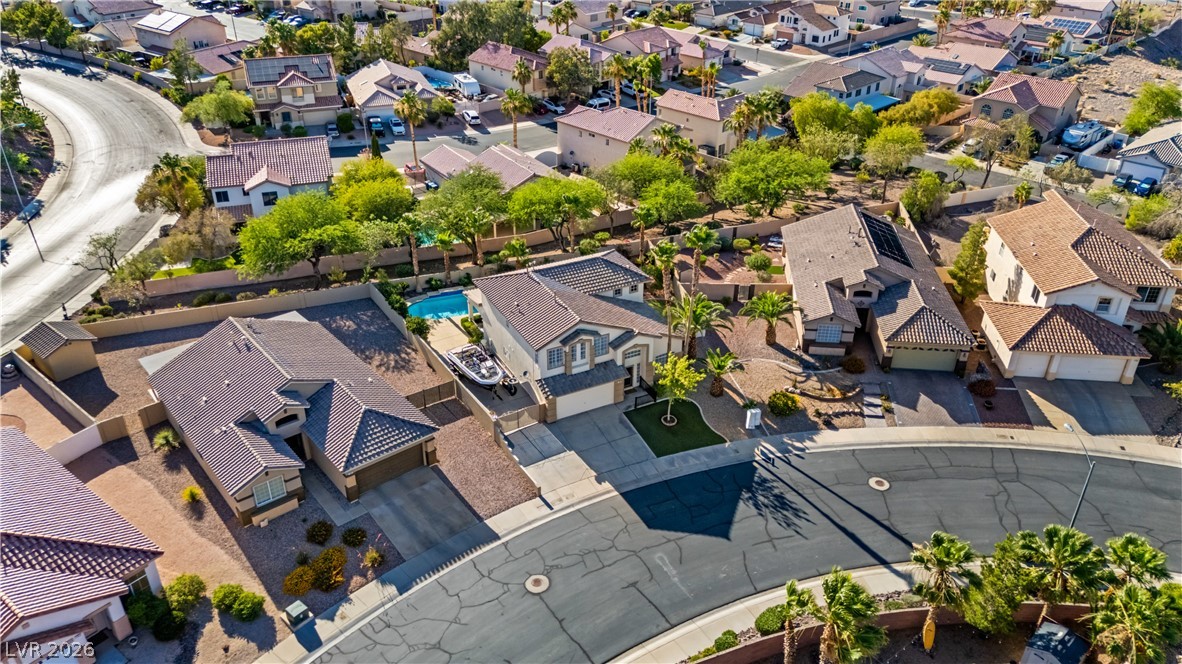 708 Vortex Avenue Henderson, NV 89002 - Photo 54 of 71 An aerial perspective reveals a vibrant neighborhood with homes featuring individual pools and solar panels, nestled along curving streets.