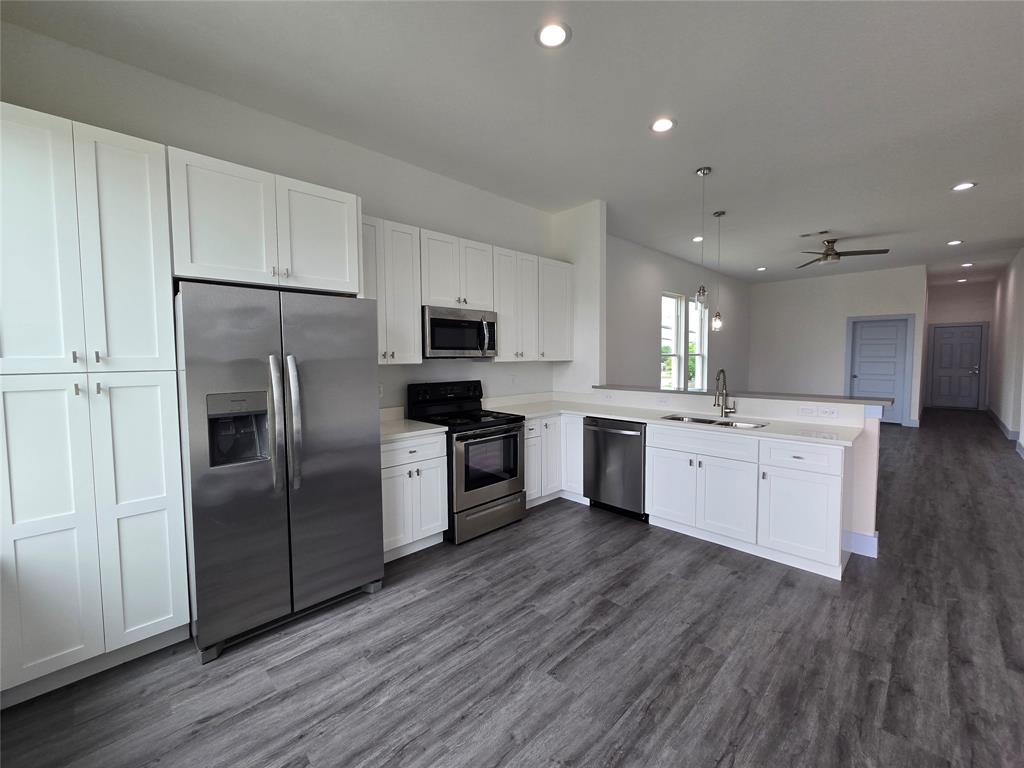 3202 Noor Street Dallas, TX 75233 - Photo 4 of 20 a large kitchen with cabinets wooden floor stainless steel appliances and a window