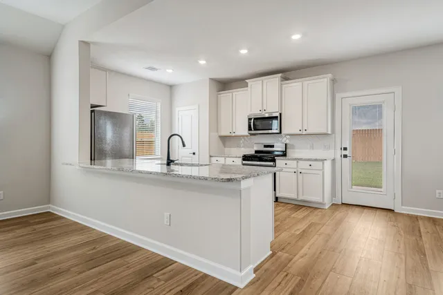 a kitchen with kitchen island granite countertop a sink cabinets and wooden floor