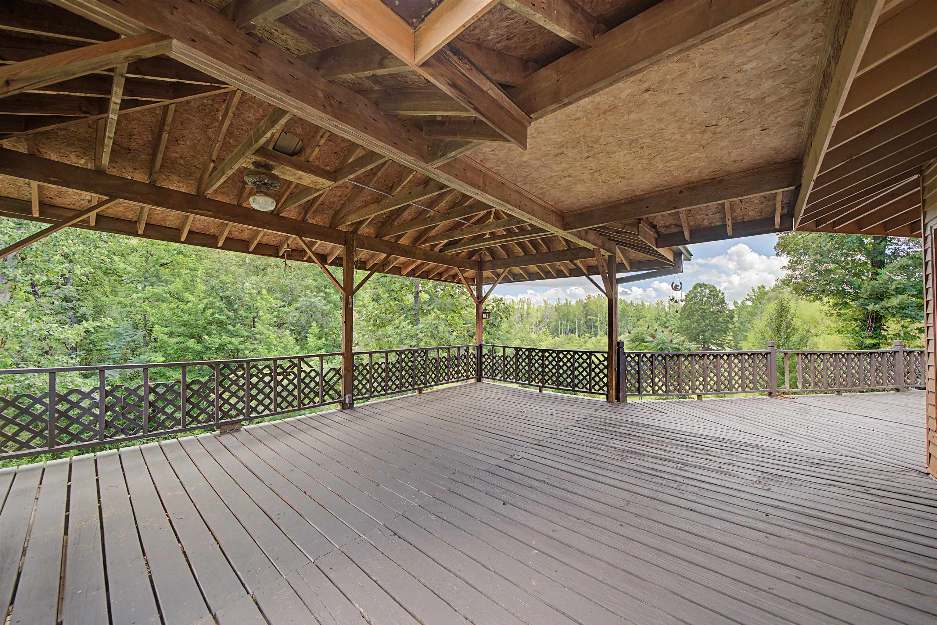 2380 Dunaway Road Selmer, TN 38375 - Photo 31 of 39 Expansive covered wood deck featuring a dark stain, decorative lattice railings, structural wood beams, and a ceiling-mounted light fixture