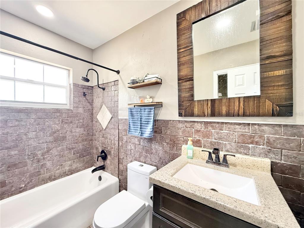 5846 Wyoming Avenue New Port Richey, FL 34652 - Photo 35 of 47 a bathroom with a granite countertop bathtub sink vanity mirror and toilet