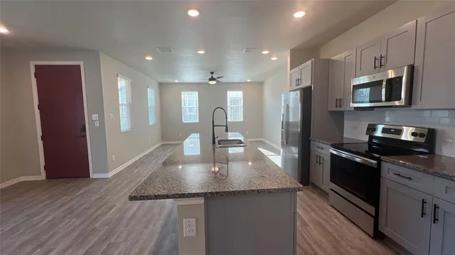 a kitchen with stainless steel appliances granite countertop a sink a stove top oven a counter space and cabinets