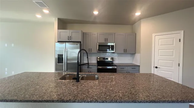 a kitchen with granite countertop a refrigerator and a sink