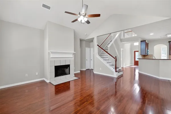 a view of an empty room with wooden floor fireplace and a window