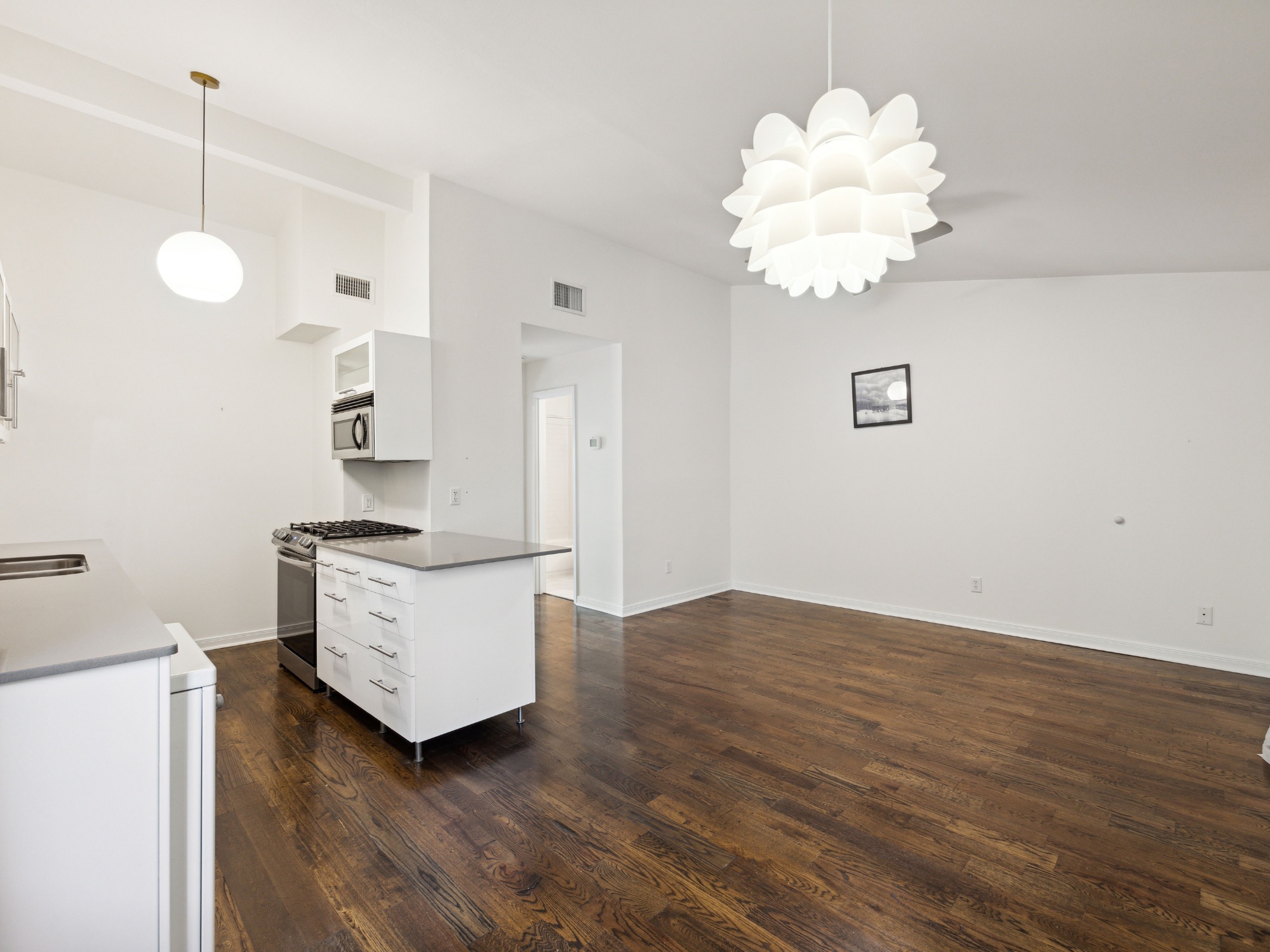 1503 West 9th Street, Unit 204 Austin, TX 78703 - Photo 3 of 21 Open-concept living space featuring wood-finish flooring, white walls, and contemporary light fixtures