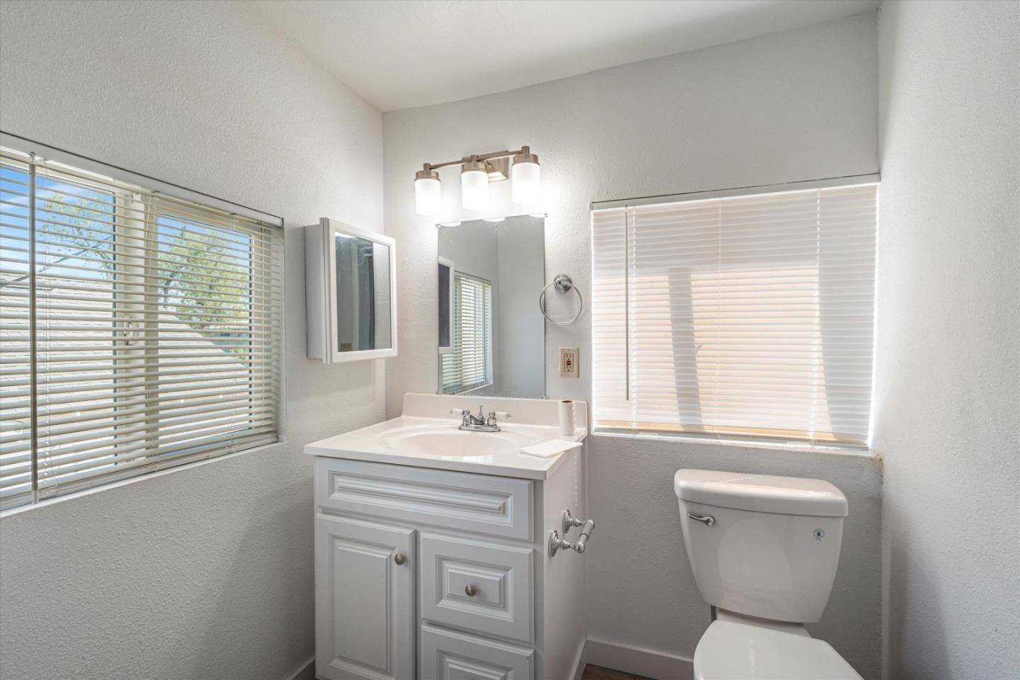 149 Covena Avenue Modesto, CA 95354 - Photo 19 of 24 a bathroom with a sink a toilet a mirror and next to a window