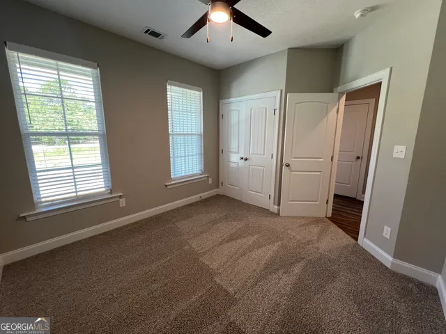 an empty room with windows and fan