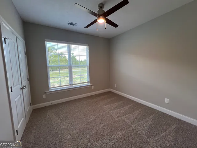 an empty room with a window and a fan