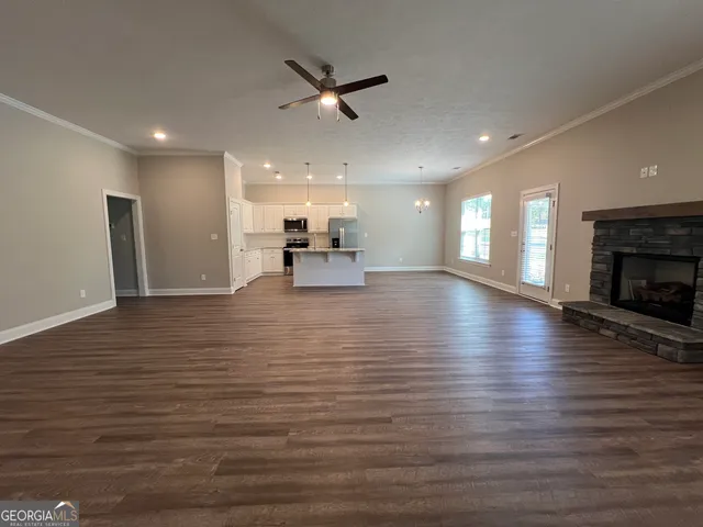 a view of a room with kitchen island a fireplace wooden floor and a window