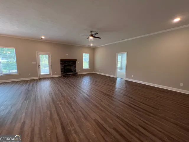 an empty room with wooden floor fireplace and windows