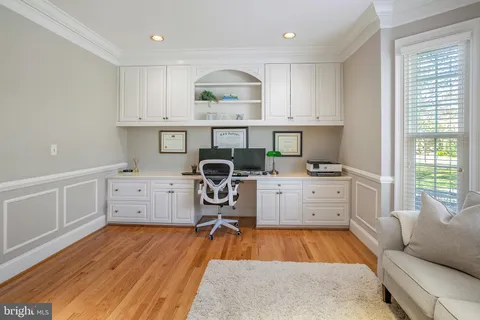 a room with a chair and white cabinets
