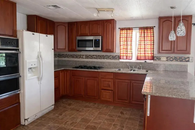 a kitchen with granite countertop a sink cabinets and stainless steel appliances