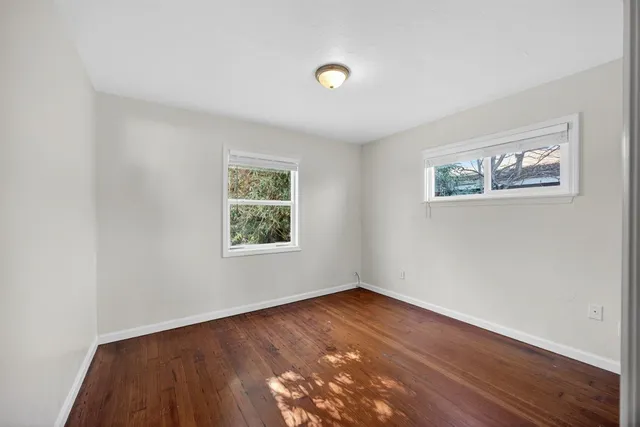 an empty room with wooden floor and window