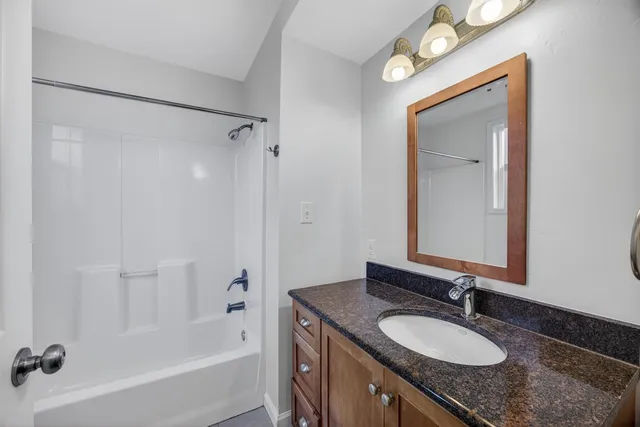 a bathroom with a granite countertop sink mirror and a bath tub