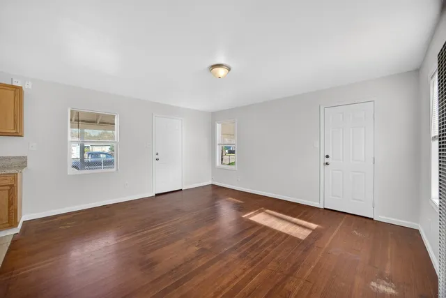 an empty room with wooden floor and windows