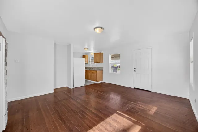 a view of empty room with wooden floor and window