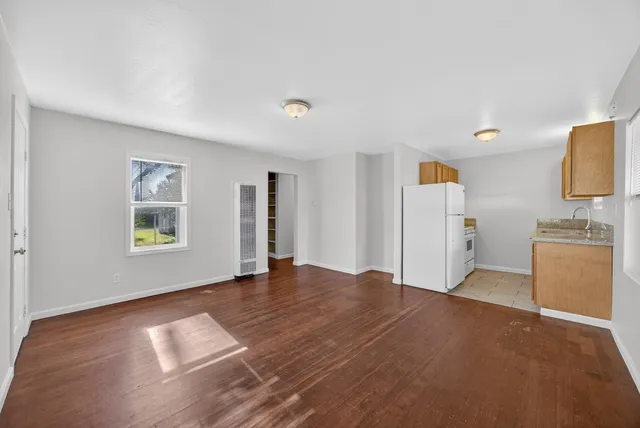 a view of an empty room with a window and a kitchen
