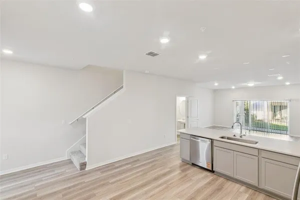 a kitchen with a sink wooden floor and white cabinets