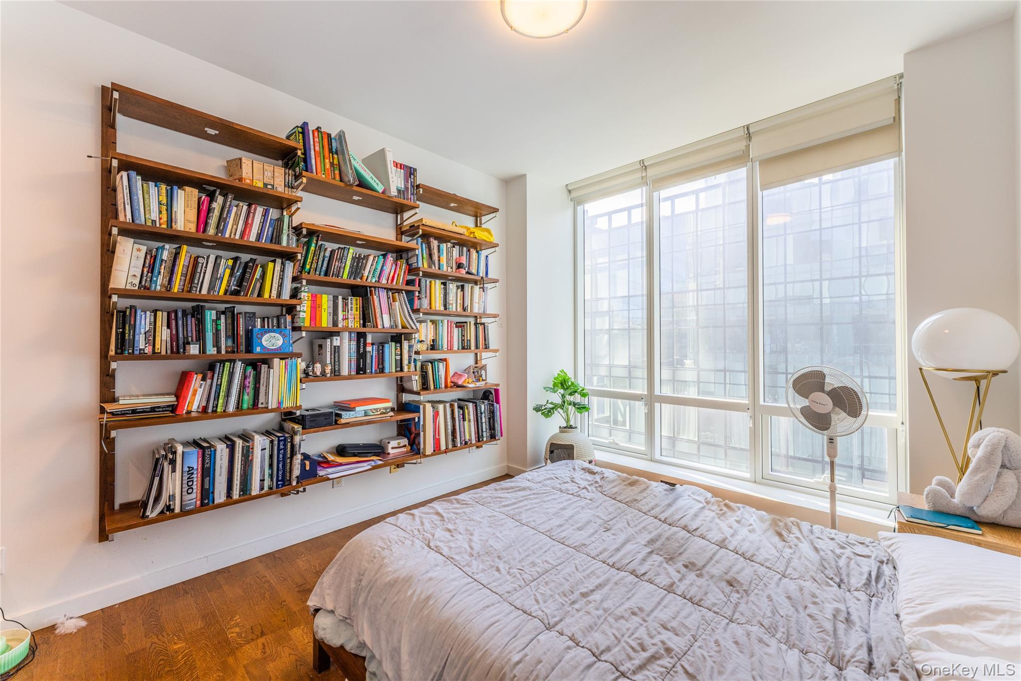 27-17 42nd Road, Unit 7E Queens, NY 11101 - Photo 18 of 42 a bedroom with a bed a book shelf and a window
