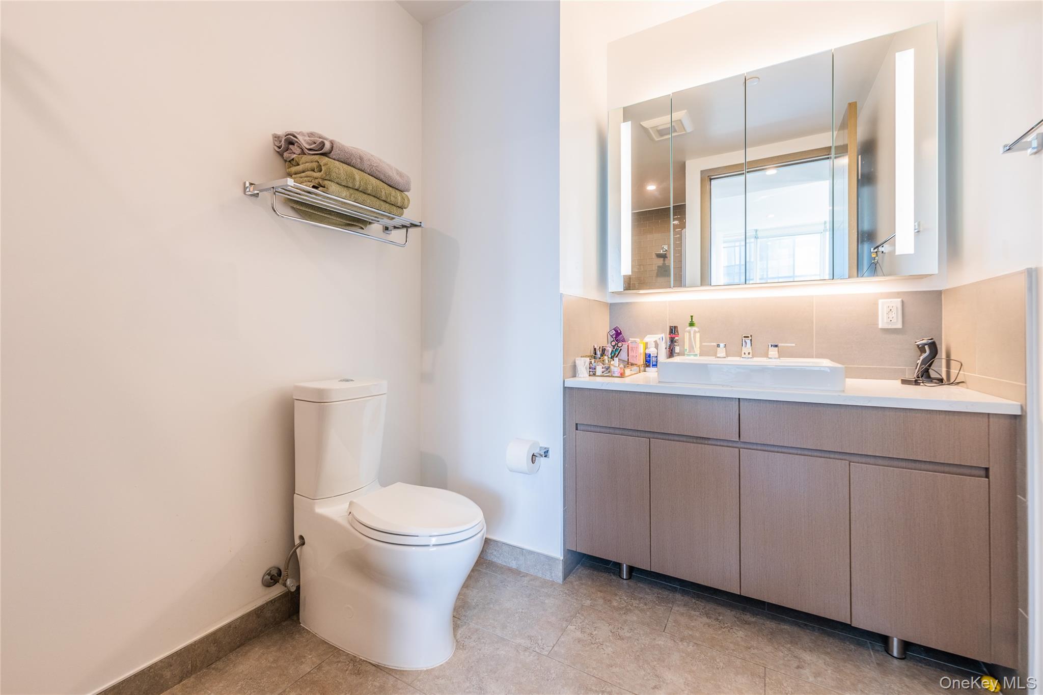 27-17 42nd Road, Unit 7E Queens, NY 11101 - Photo 22 of 42 a bathroom with a granite countertop toilet sink and mirror