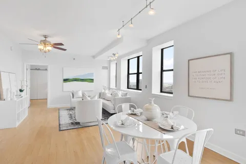 a living room with furniture a chandelier fan and a window
