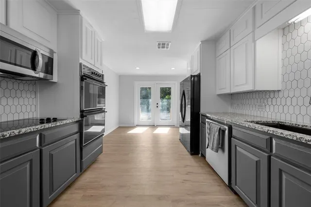 a kitchen with stainless steel appliances granite countertop a stove a sink and a refrigerator