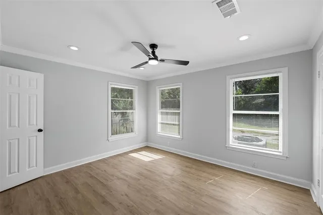 a view of an empty room with a window and wooden floor