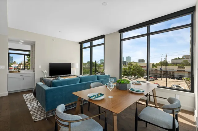 a living room with furniture a flat screen tv and a large window