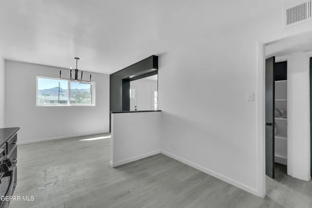 a view of an empty room with window and wooden floor