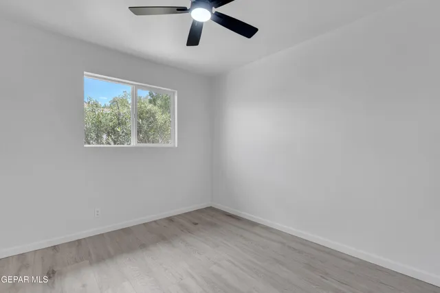 an empty room with a window and a ceiling fan